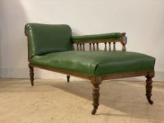 A late Victorian oak chaise longue, upholstered in faux green leather, turned supports moving on