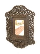 An early 20th century Anglo-Indian wall mirror, the frame pierce carved with floral arabesque and