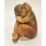 A Lladro Spanish pottery Eskimo boy seated figure decorated with brown glaze, signed verso, (17cm