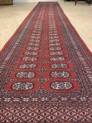 A bokhara runner rug, hand knotted, with two rows of guls within a multi line border 610cm x 84cm
