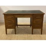 An oak desk, mid 20th century, the top inset with skiver writing surface over two slides, one long