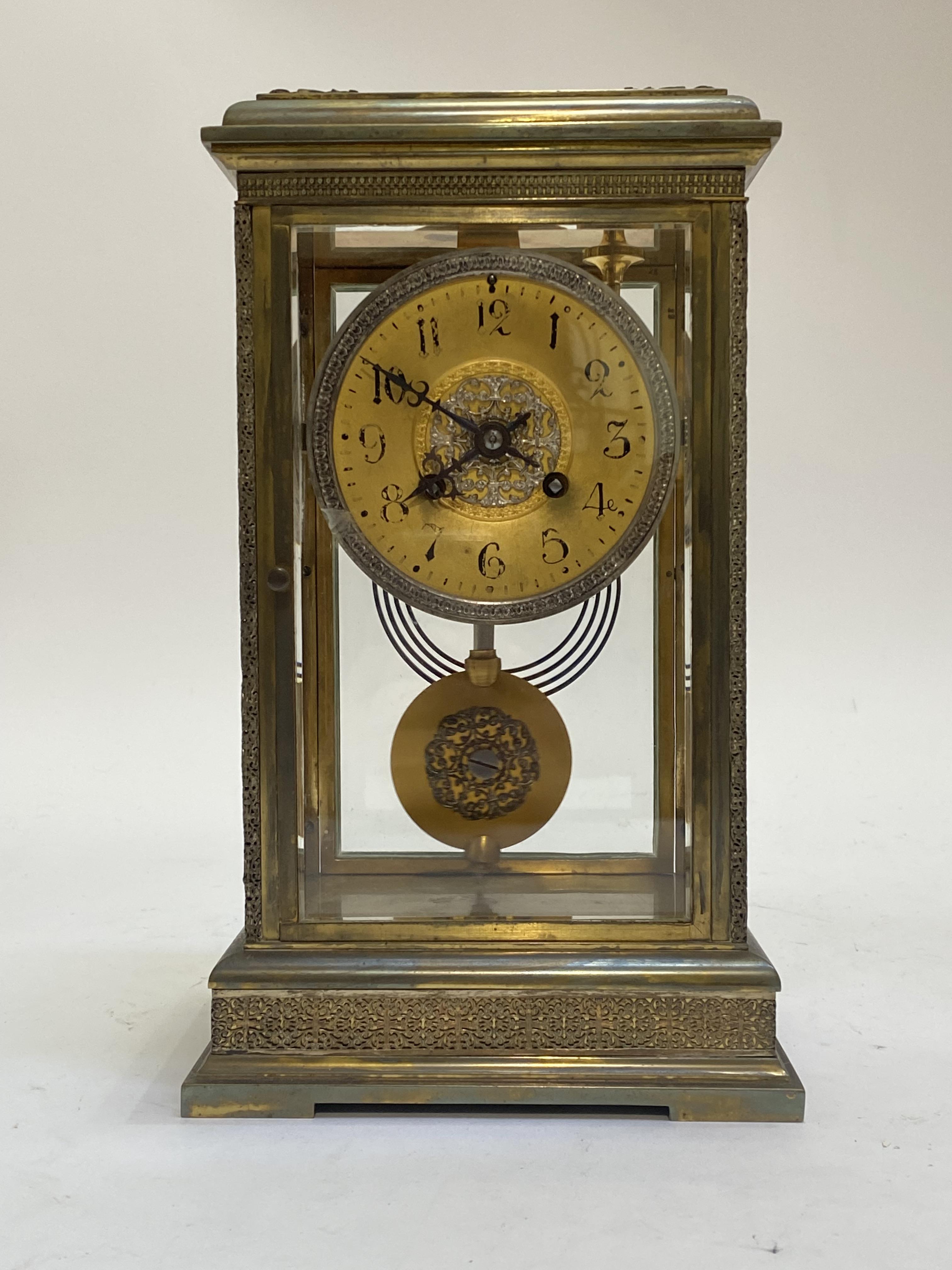 A French brass and four glass clock, circa 1890, the case with filigree frieze, pilasters and