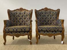 A pair of carved walnut upholstered armchairs in the baroque taste, H105cm, W80cm, D65cm