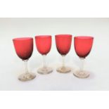 A set of four Edwardian cranberry glass cordial glasses on clear stems and circular bases, (13.2cm