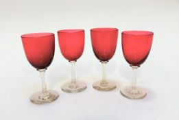 A set of four Edwardian cranberry glass cordial glasses on clear stems and circular bases, (13.2cm