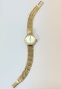 A 9ct gold lady's Omega wristwatch with silver dial and baton hour markers, on milanese bracelet (