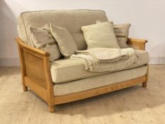 Ercol, a blonde elm and beech bergere two seat sofa, upholstered in oatmeal chenille fabric, with