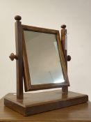 An early 20th century walnut toilet mirror, the rectangular glass swiveling between reeded uprights,