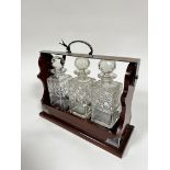 A mahogany Epns mounted tantalus complete with set of three crystal slice cut square whisky