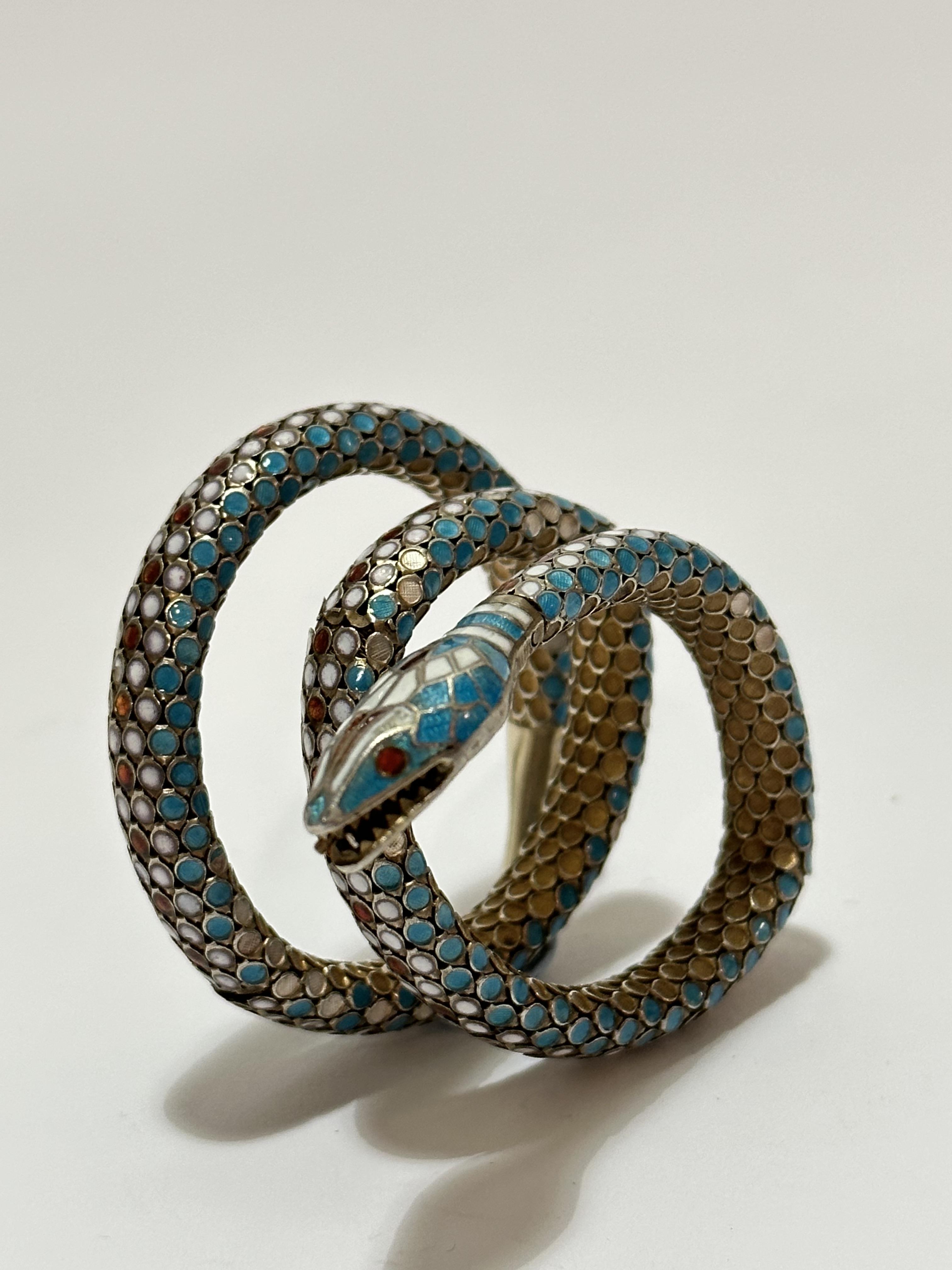 An Eastern silver gilt enamelled serpent triple coil bracelet with open mouth and inset enamelled