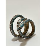 An Eastern silver gilt enamelled serpent triple coil bracelet with open mouth and inset enamelled
