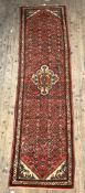 A Persian Hamadan design runner rug, hand knotted, red ground with medallion and spandrels 300cm x