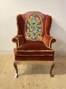 A Queen Anne style upholstered wingback armchair, raised on palmette carved cabriole supports with