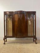 An Edwardian mahogany break bow front display cabinet with astragal glazed doors raised on