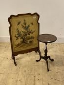 A 1920's walnut fire screen, the undulating frame enclosing a painted panel depicting a lotus
