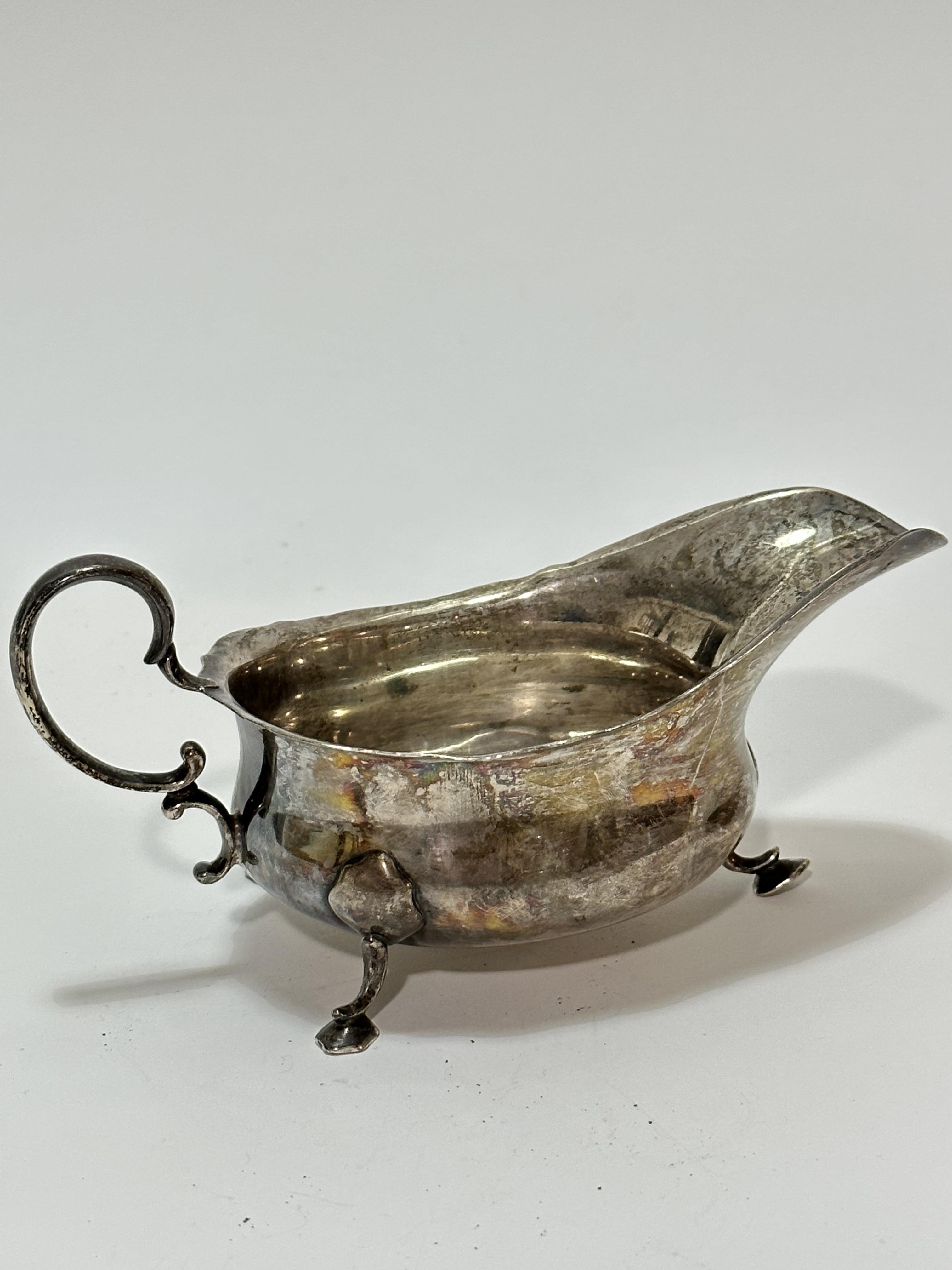 A Birmingham silver George III style scalloped sauce boat with C scroll handle to side, raised on