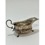 A Birmingham silver George III style scalloped sauce boat with C scroll handle to side, raised on