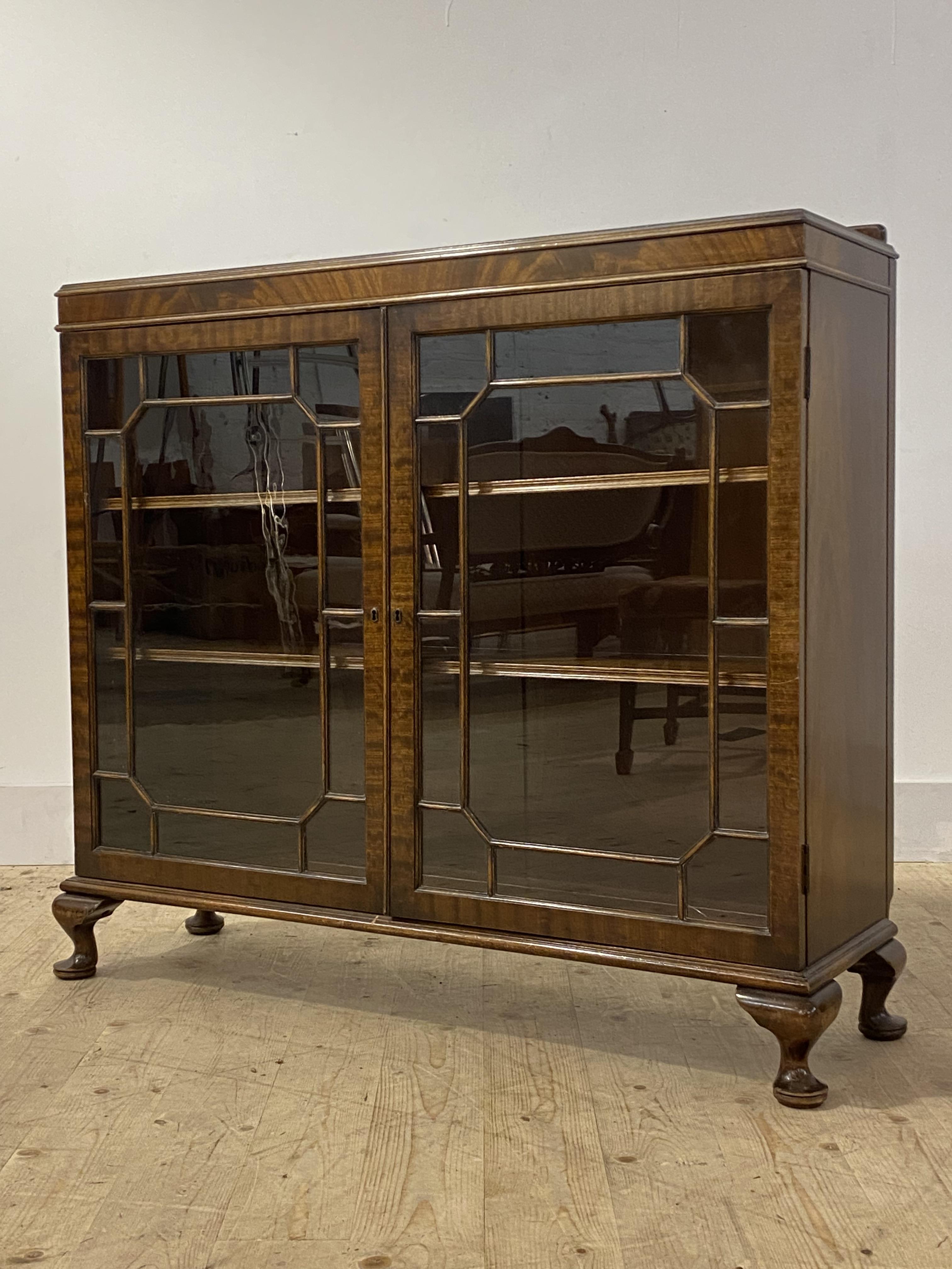 A mahogany display cabinet, second quarter of the 20th century, the ledge back over two astragal
