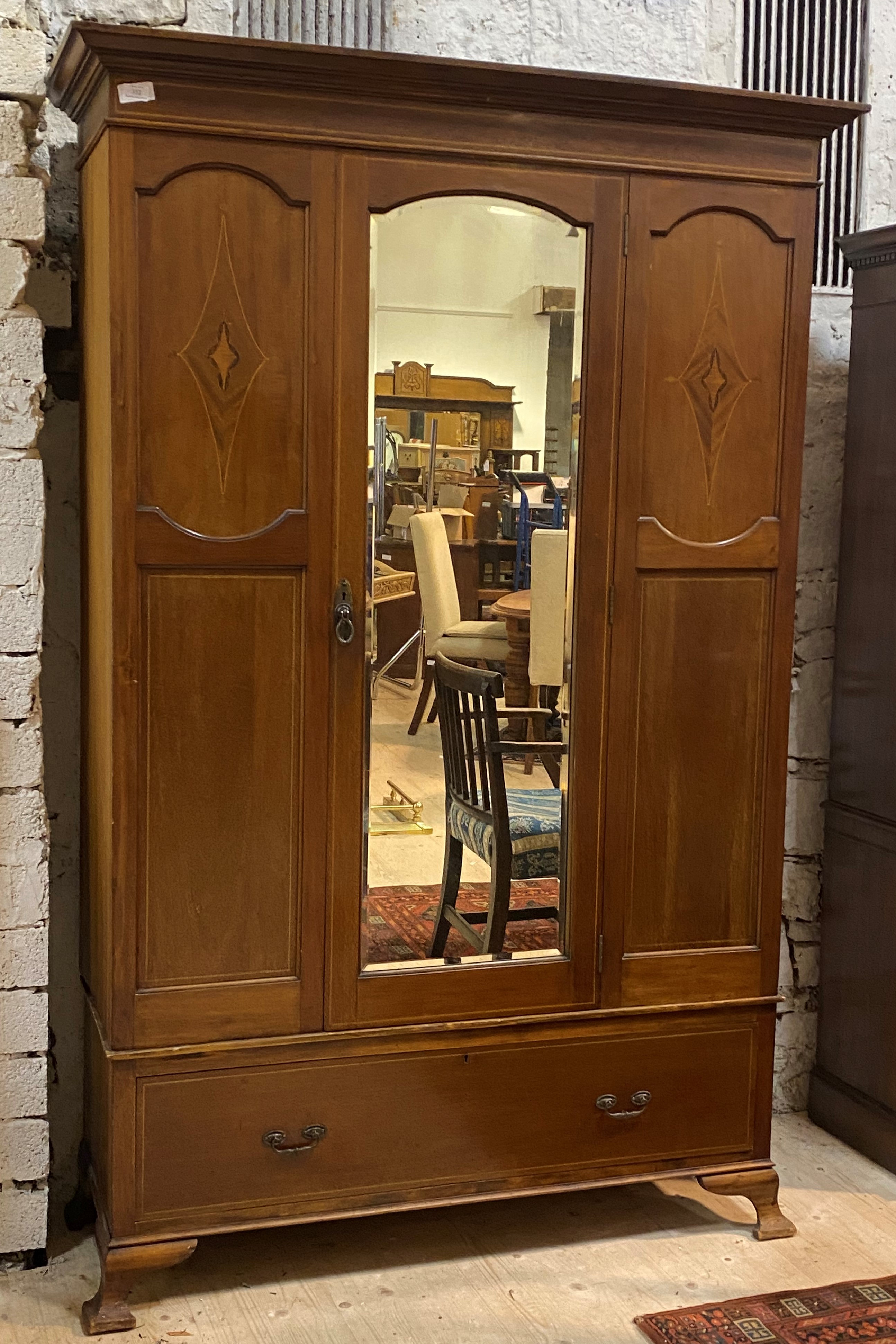 An Edwardian inlaid mahogany wardrobe, the projecting cornice over bevel glazed mirror door