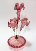 An Edwardian pale pink cranberry glass four branch epergne, the centre of iris style design with