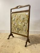 An early 20th century fire screen, the mahogany frame enclosing an emboridered panel worked in a