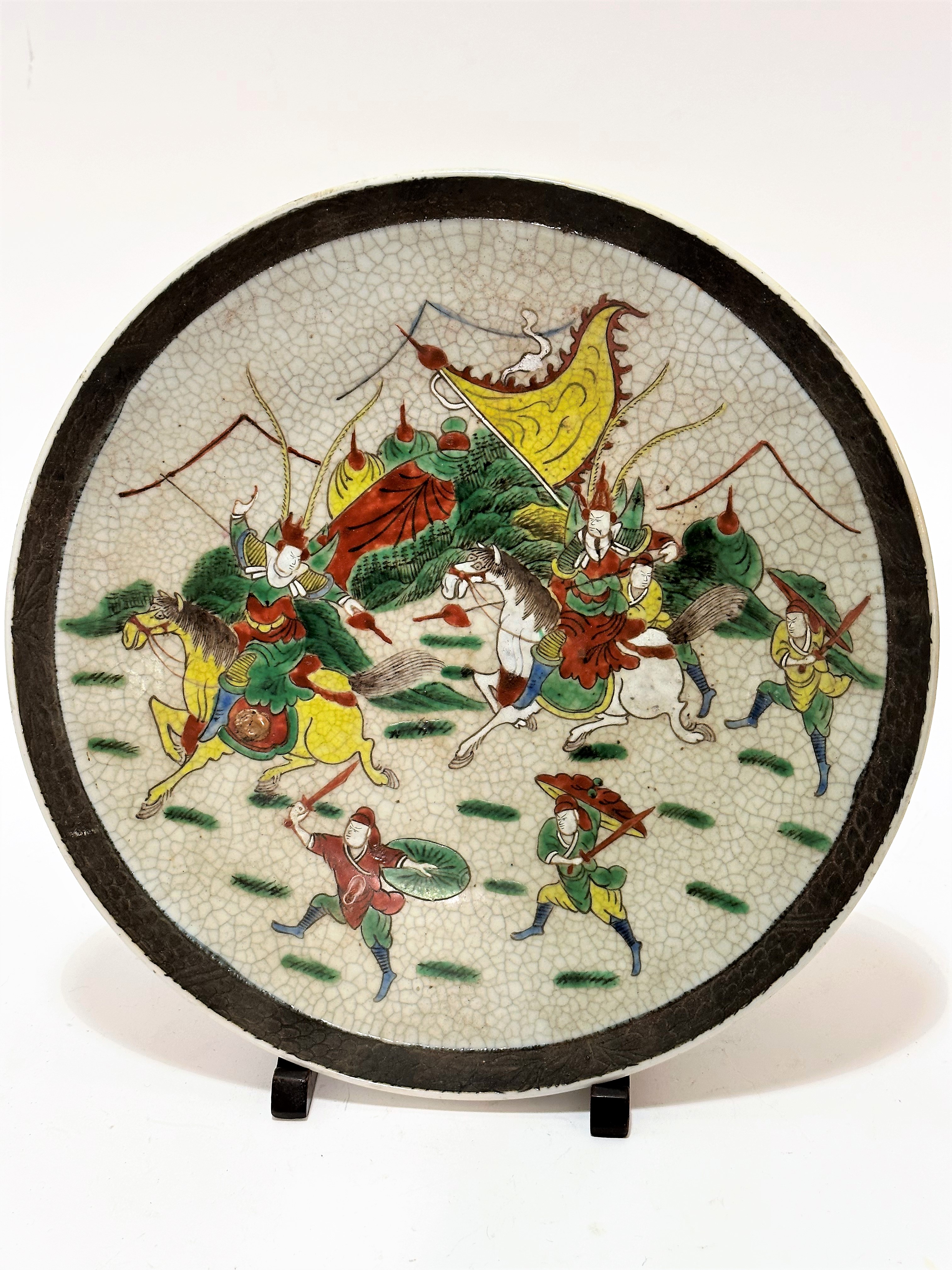 A Japanese craquelure ware charger decorated with Samurai figures on horseback and attendant