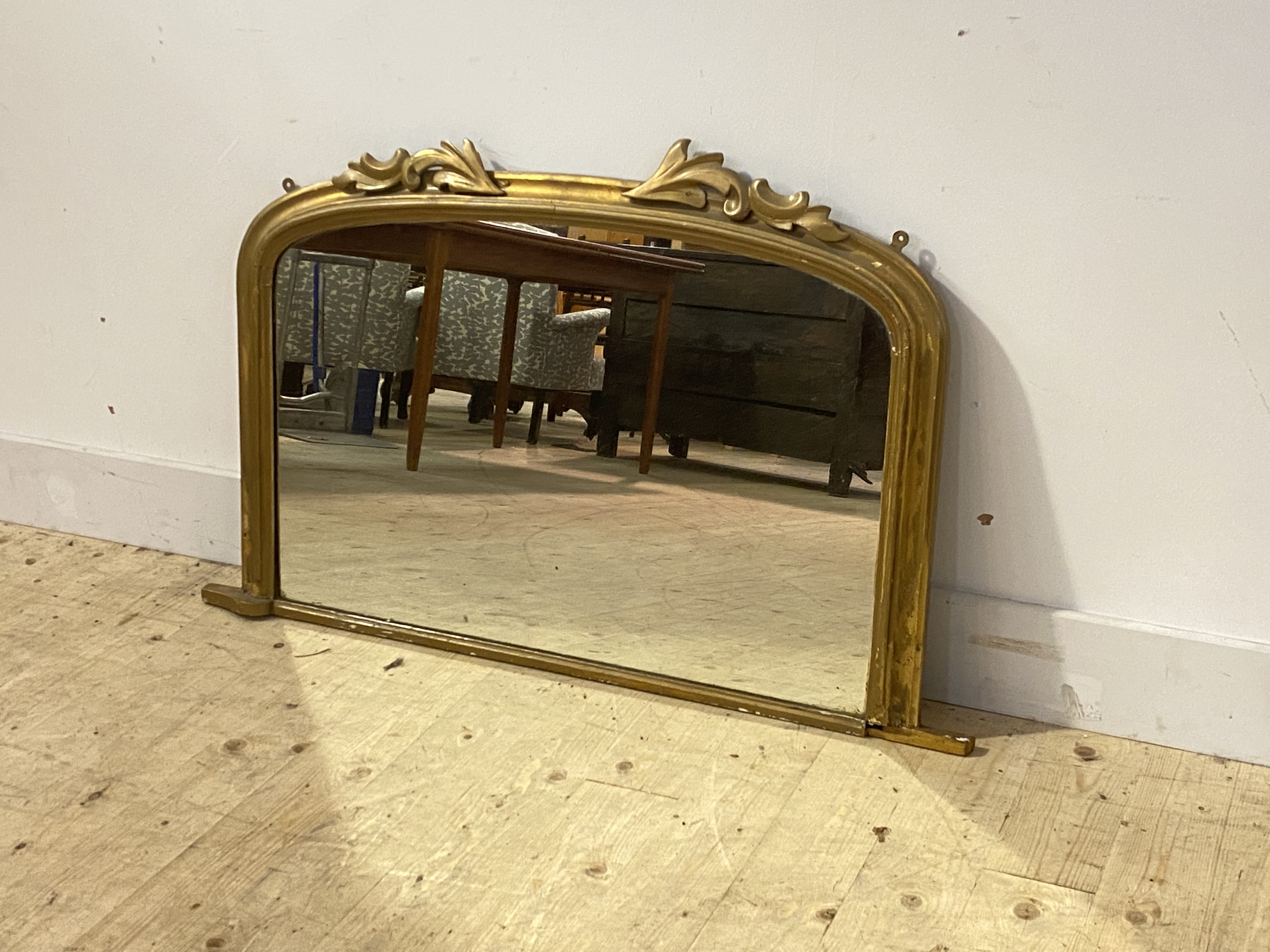 A Victorian overpainted gilt framed over mantel mirror, the arched top with carved acanthus leaf