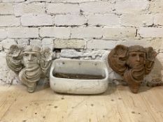 A near pair of wall pocket planters formed as masks, together with a glazed terracotta wall pocket