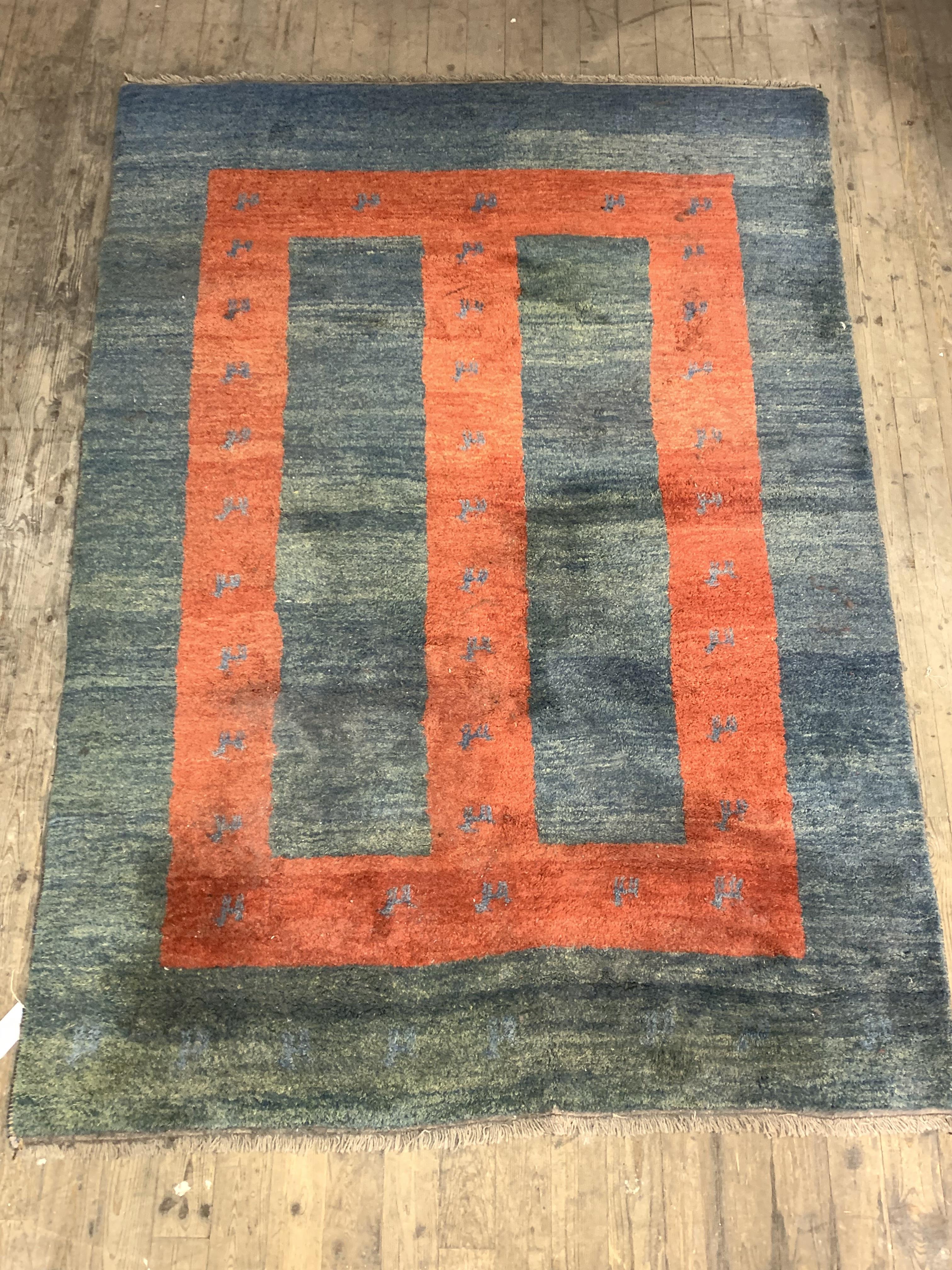A Persian style Gabbeh rug, hand knotted, the abrashed blue ground with geometric red panel and