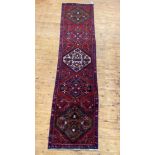 A Persian runner rug, hand knotted, the red field with five lozenge medallions and bordered 326cm