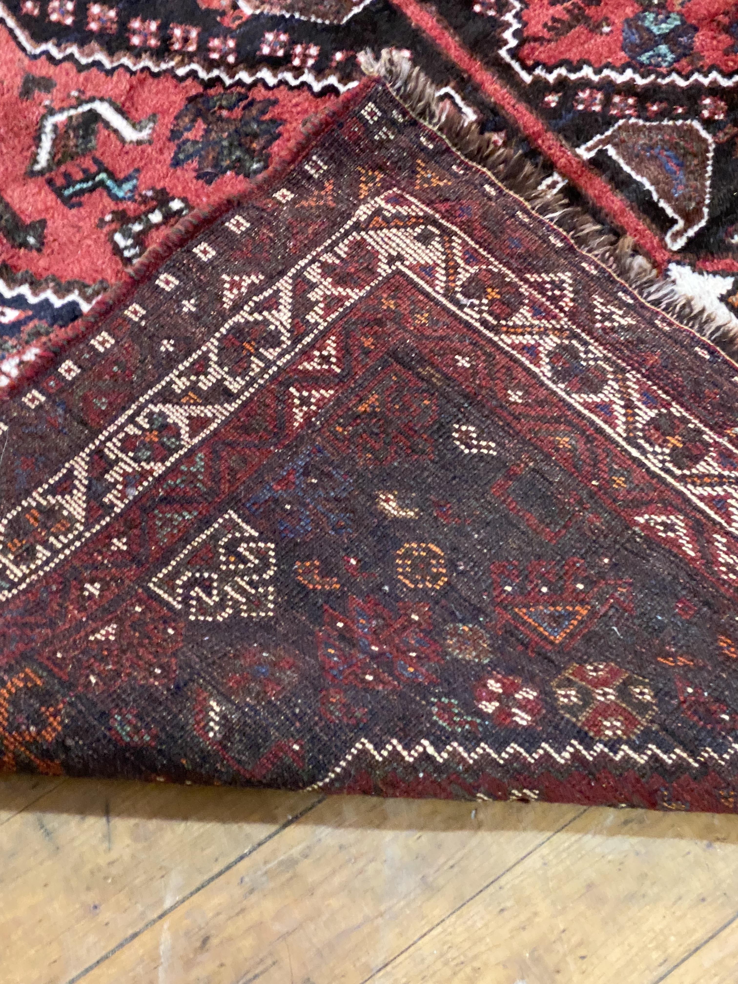 A Persian Shiraz rug, hand knotted, the red field with pole medallion flower heads and birds, within - Image 3 of 3