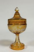 A 19th century Bohemian etched amber glass jar and cover, the cover with faceted knop and etched