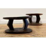 A pair of African tribal stools, circular dished seats raised on shaped pierced supports over a