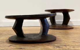 A pair of African tribal stools, circular dished seats raised on shaped pierced supports over a