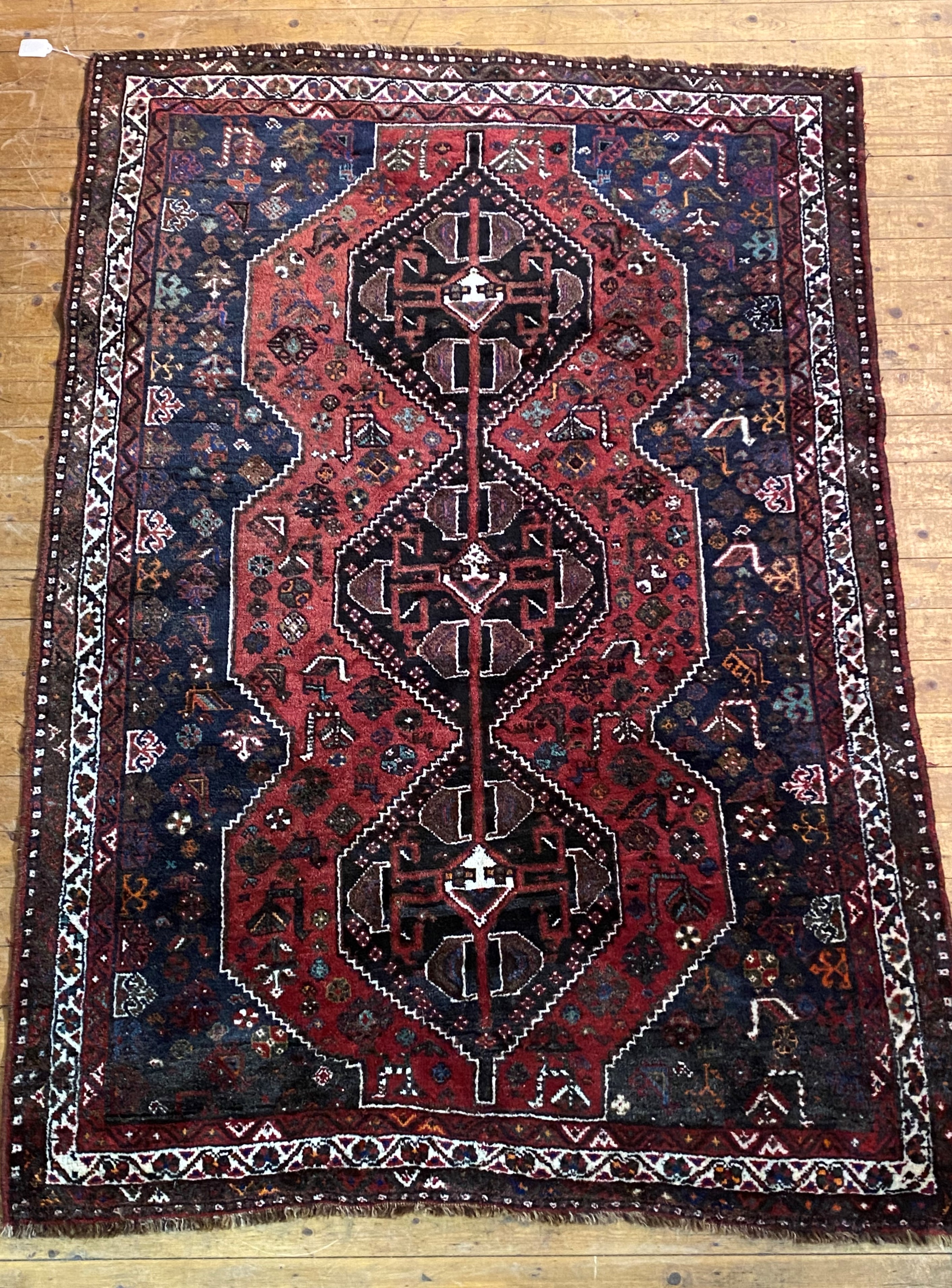 A Persian Shiraz rug, hand knotted, the red field with pole medallion flower heads and birds, within