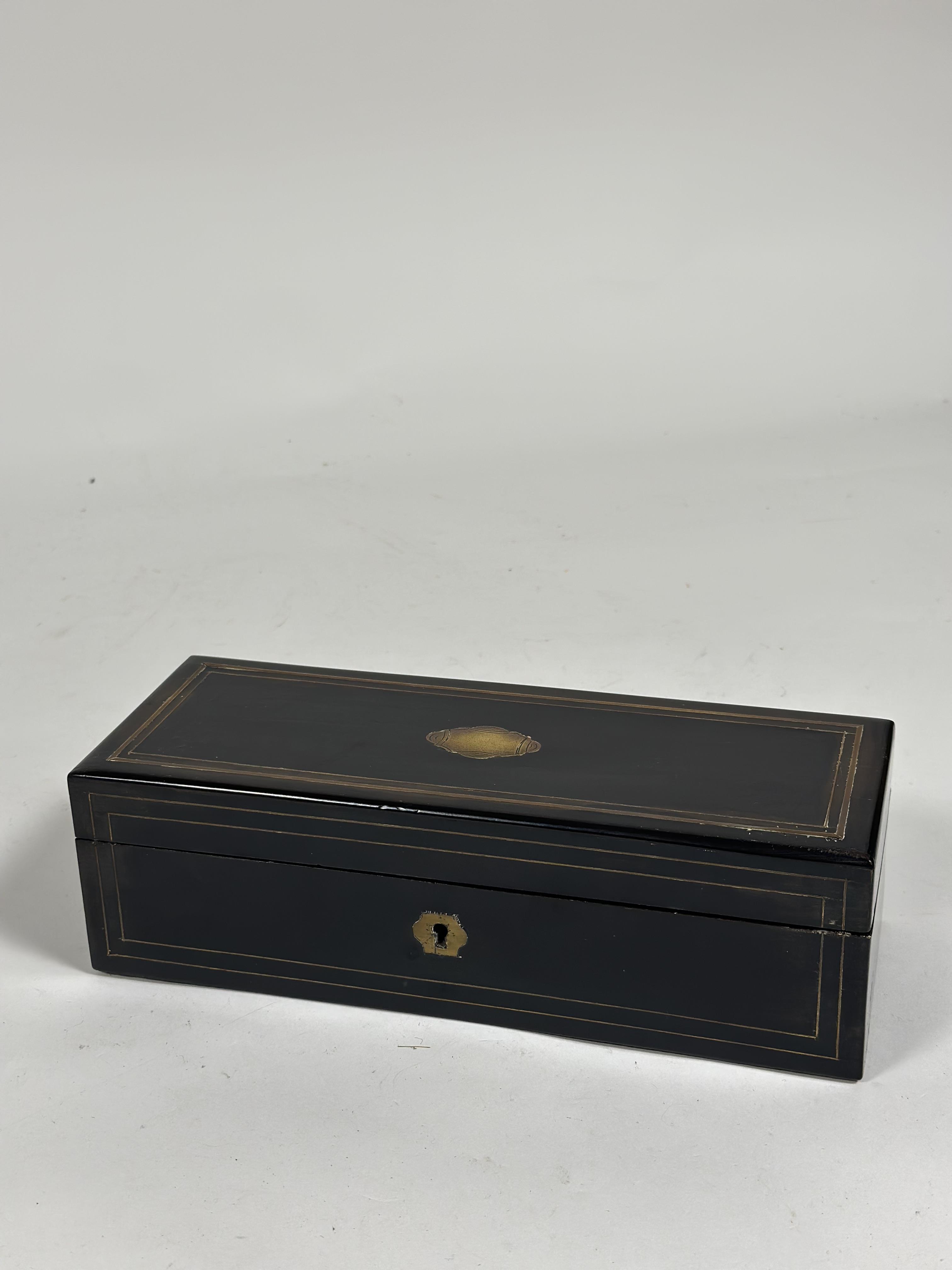 An early 19th century brass-inlaid ebony glove box, of plain oblong form, containing three pairs