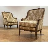 A pair of French walnut bergere armchairs in the Louis XV style, circa 1900, the ribbon carved crest