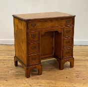 A figured elm kneehole desk of 18th century design, circa 1930, the cross banded and boxwood