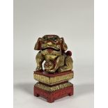 A Chinese red lacquer model of a Buddhistic lion, modelled with fabric ball on an integral stand,