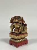 A Chinese red lacquer model of a Buddhistic lion, modelled with fabric ball on an integral stand,