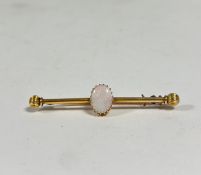 An opal-set yellow metal bar brooch, the oval-cut opal on a cylindrical bar with reeded ball