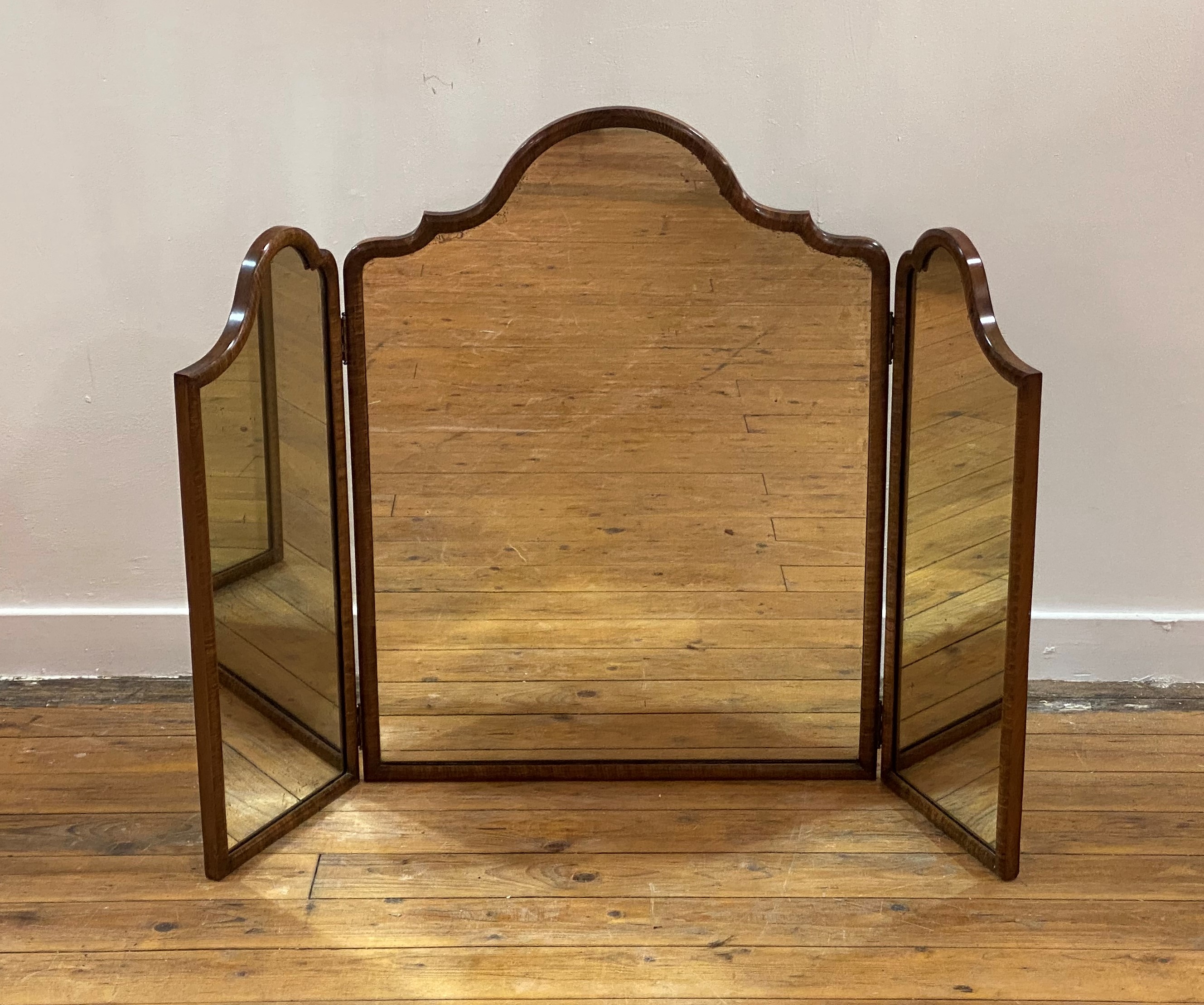 An 18th century style walnut framed triptych toilet mirror, circa 1920s, the top of undulating form.