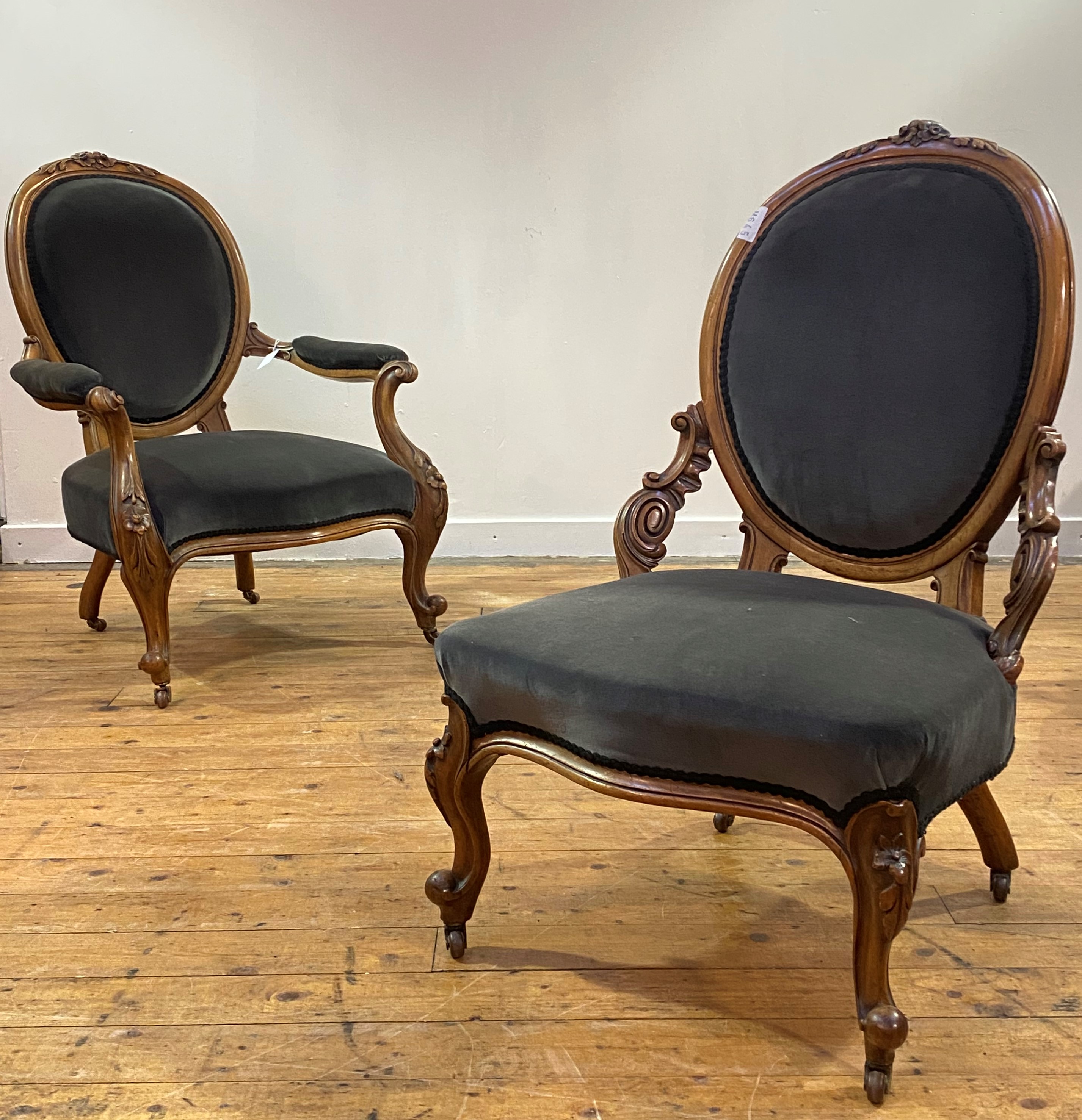 A pair of mid Victorian His and Hers walnut framed easy chairs, the oval back with floral carved