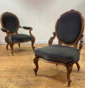 A pair of mid Victorian His and Hers walnut framed easy chairs, the oval back with floral carved