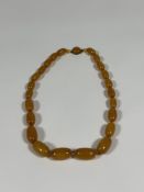 A single graduated strand of "butterscotch" amber beads with small amber spacers, on an amber-