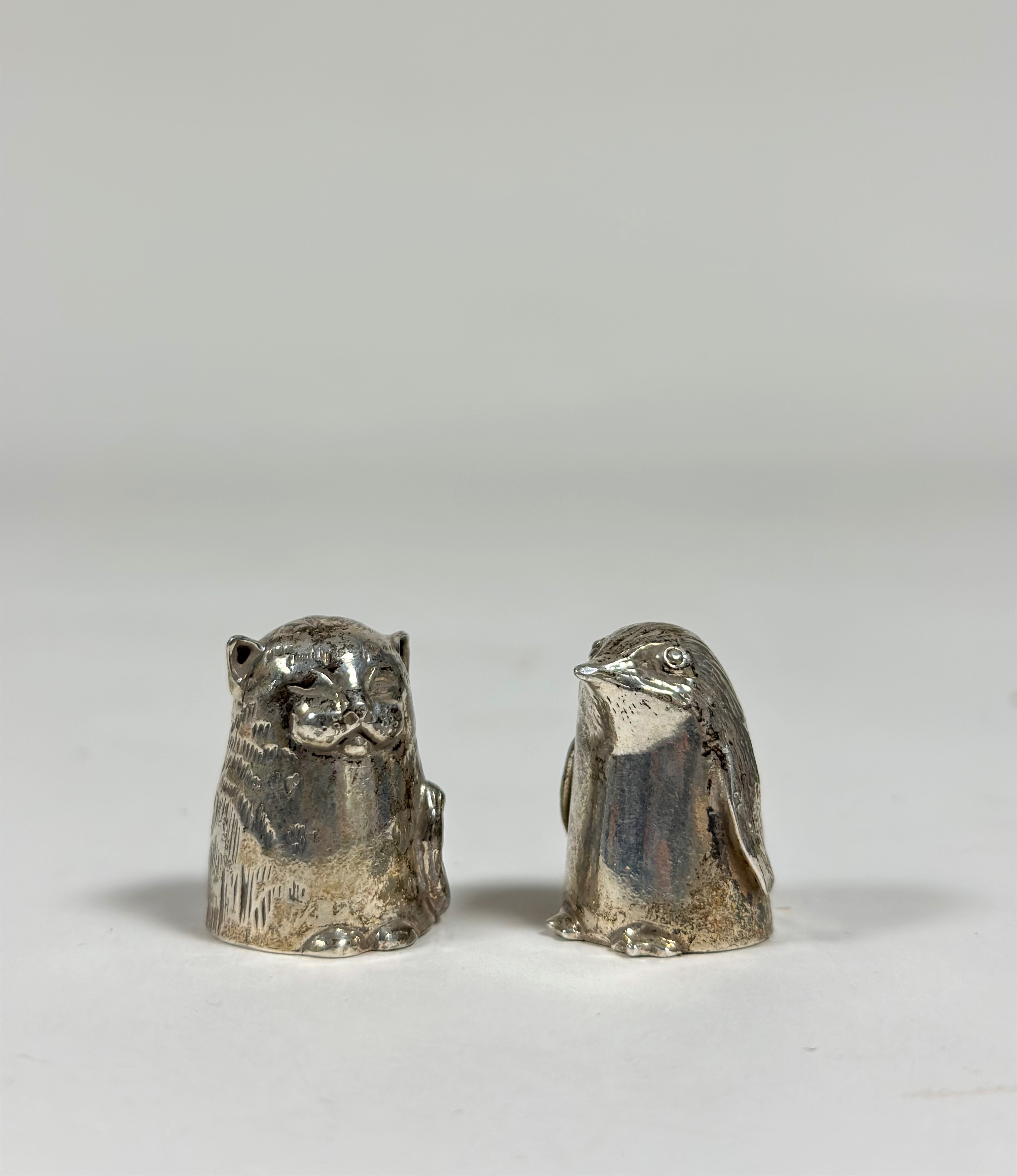 Two silver novelty thimbles: a seated cat, Clive & Clarissa Cooke, London 1984; and a penguin,
