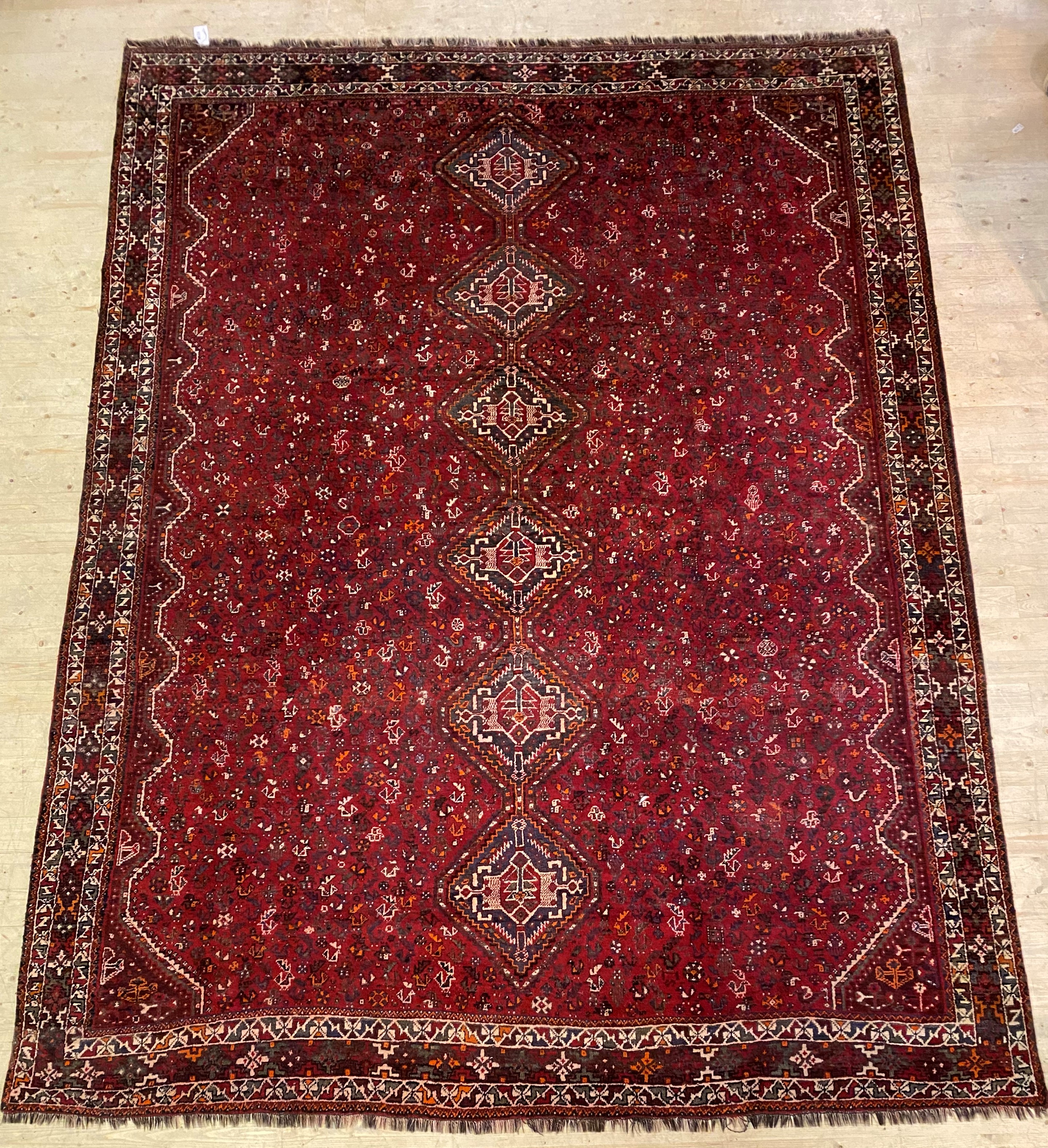 A Shiraz hand knotted carpet, the red field with pole medallion and intricately decorated with