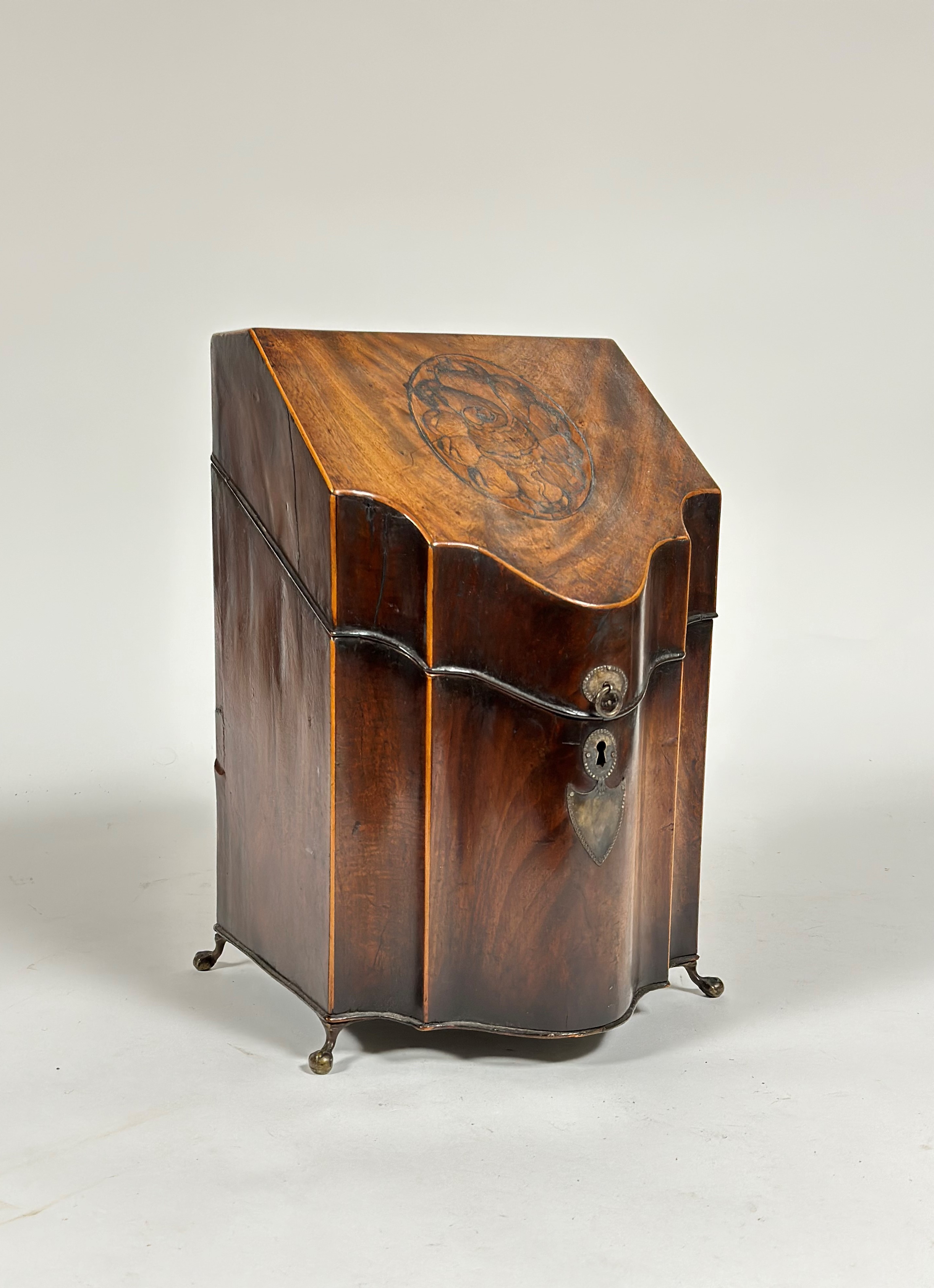 A George III inlaid mahogany knife box, of serpentine form, the hinged cover with (faded) conch