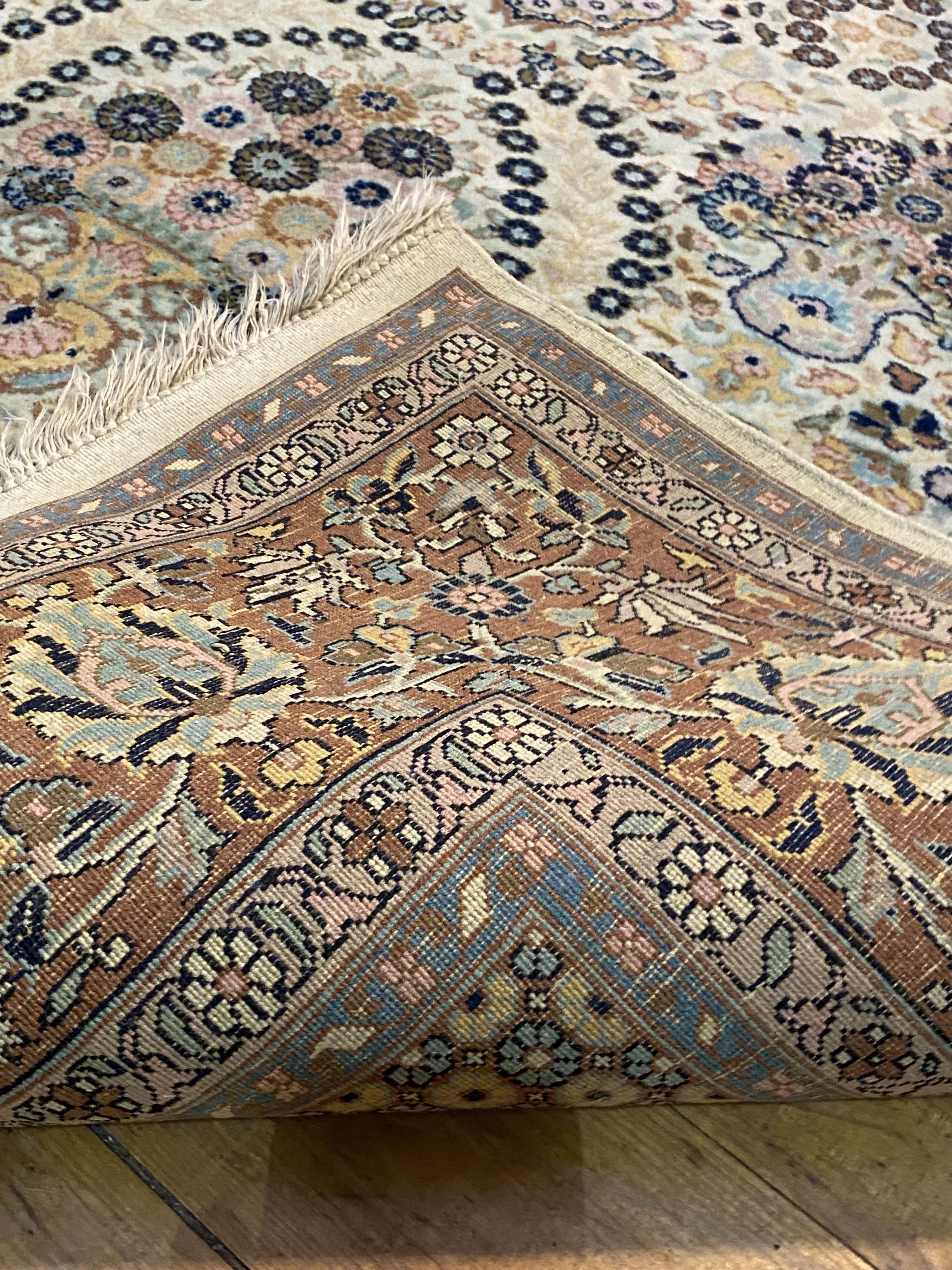 A Persian Tabriz carpet, hand knotted, the ivory field decorated with repeating flower heads and - Image 3 of 3
