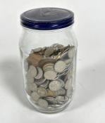 A jar containing a large collection of United Kingdom currency, including silver six pences, metal